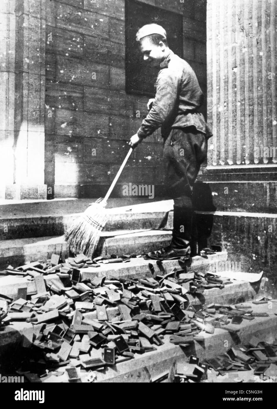 Russian soldier cleans Nazi propaganda material, the Reichstag, Berlin, Germany, World War II, 1945 Stock Photo