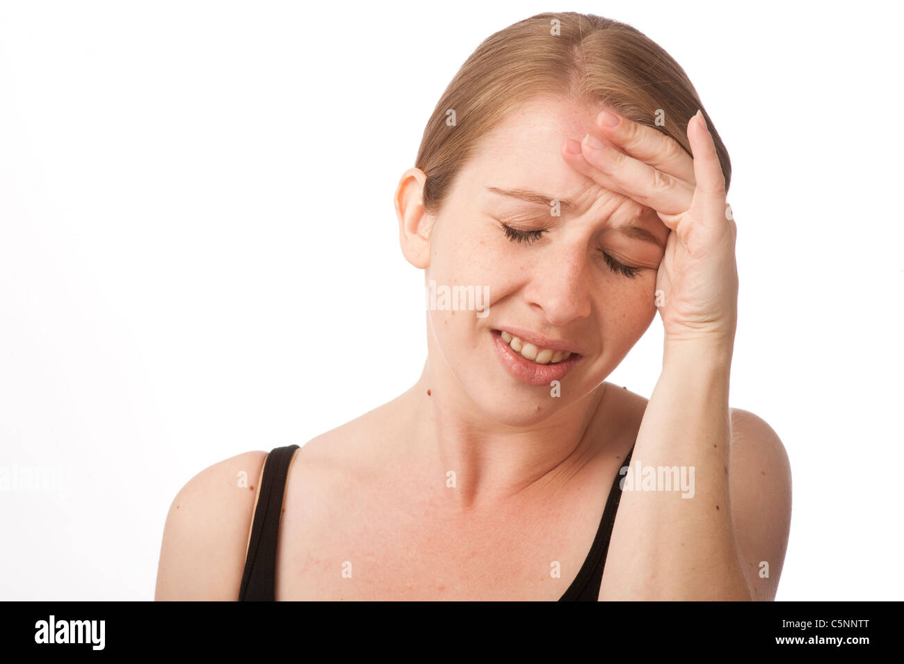 a young caucasian woman with a headache rubbing her forehead to relieve ...