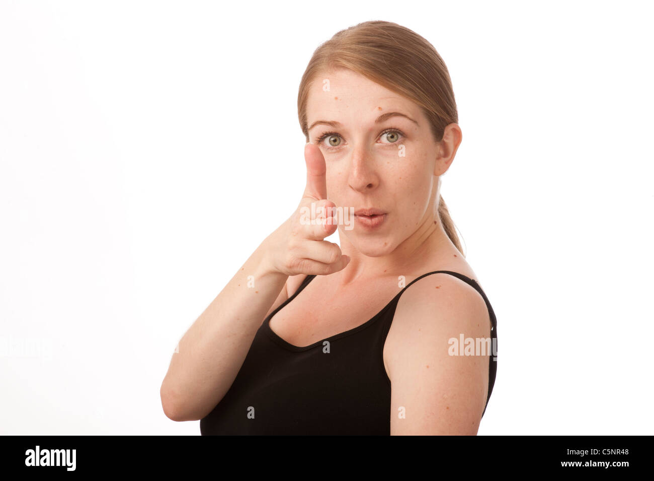 a young caucasian woman using her fingers as a pretend gun, shooting with her finger Stock Photo