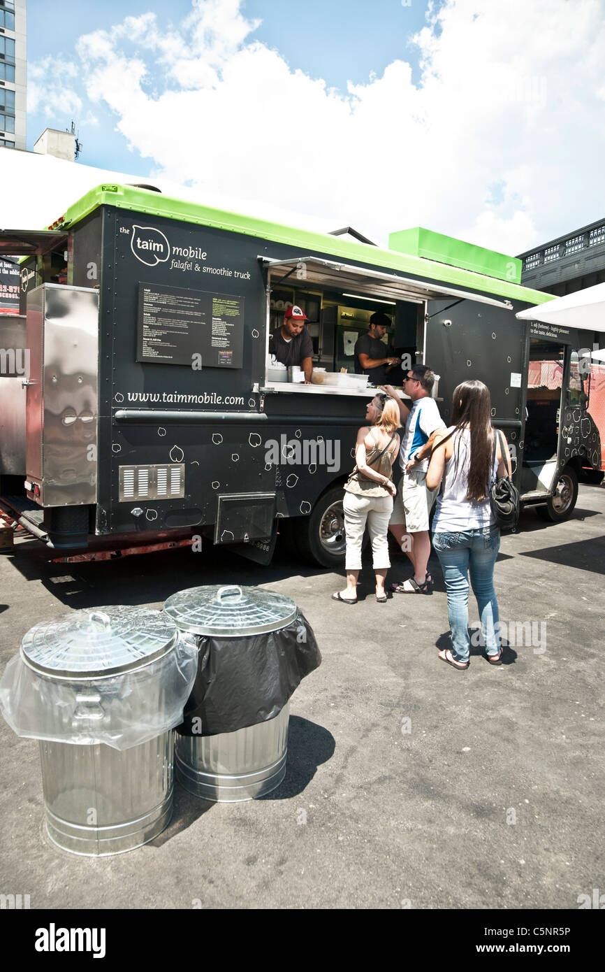 happy customers line up at falafel food truck in lot next to High Line elevated park entrance Chelsea neighborhood New York City Stock Photo