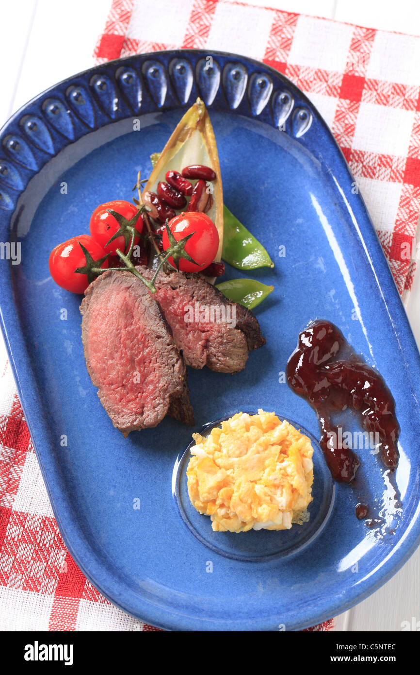 Slices of roast beef, scrambled eggs and vegetable garnish Stock Photo