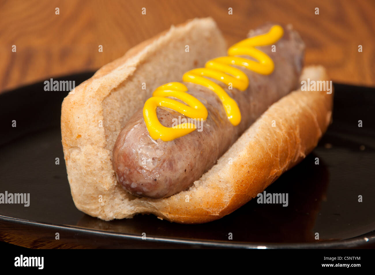 Cooked Bratwurst on a bun topped with Mustard Stock Photo Alamy