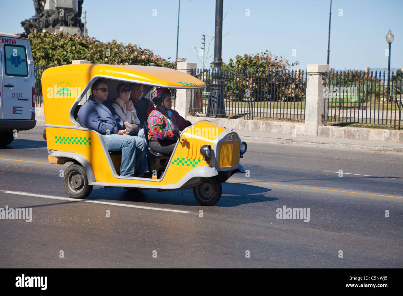 Cuba, Havana. Three-wheeled Taxi with Three Passengers and Driver. Stock Photo