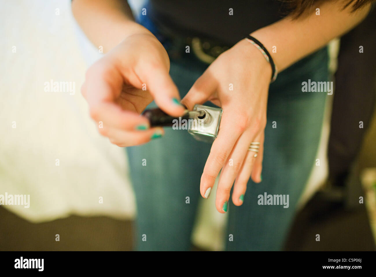 Teenage girl painting fingernails with nail varnish Stock Photo