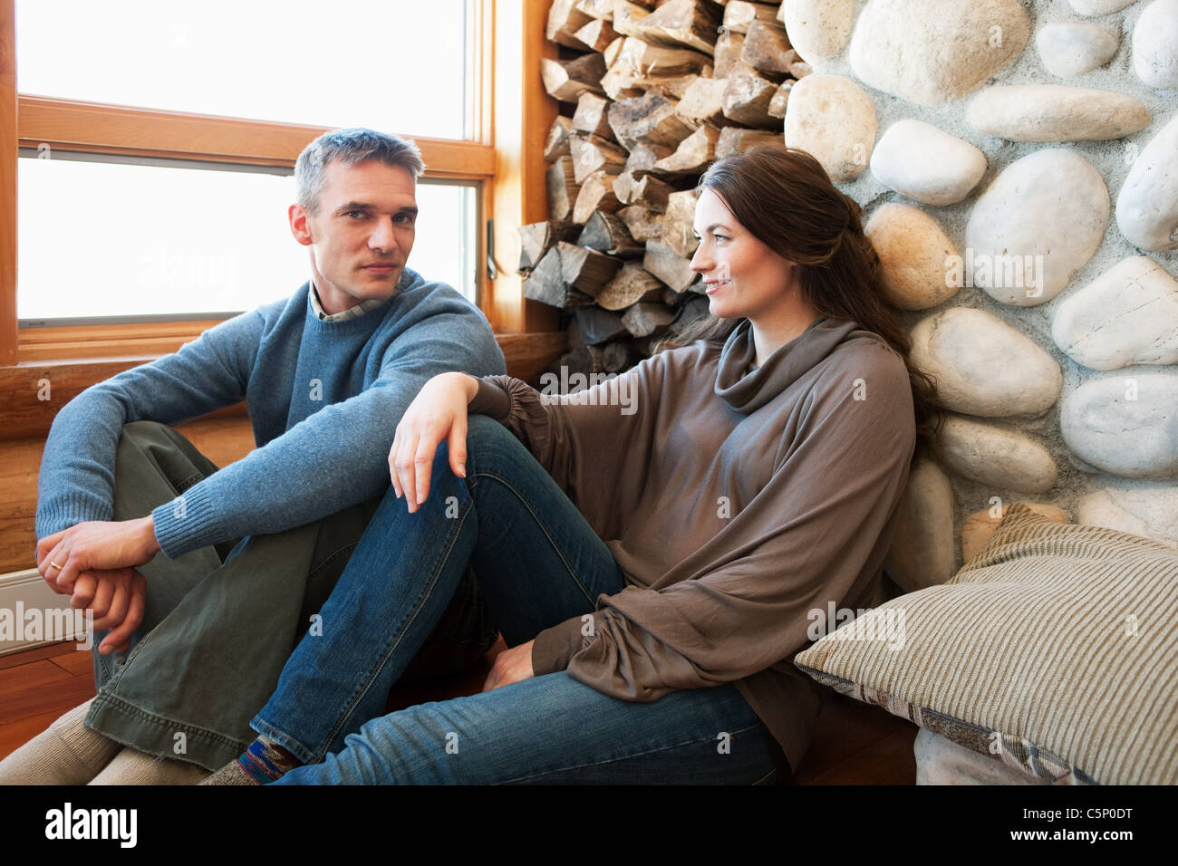 Mid adult couple sitting in log cabin Stock Photo