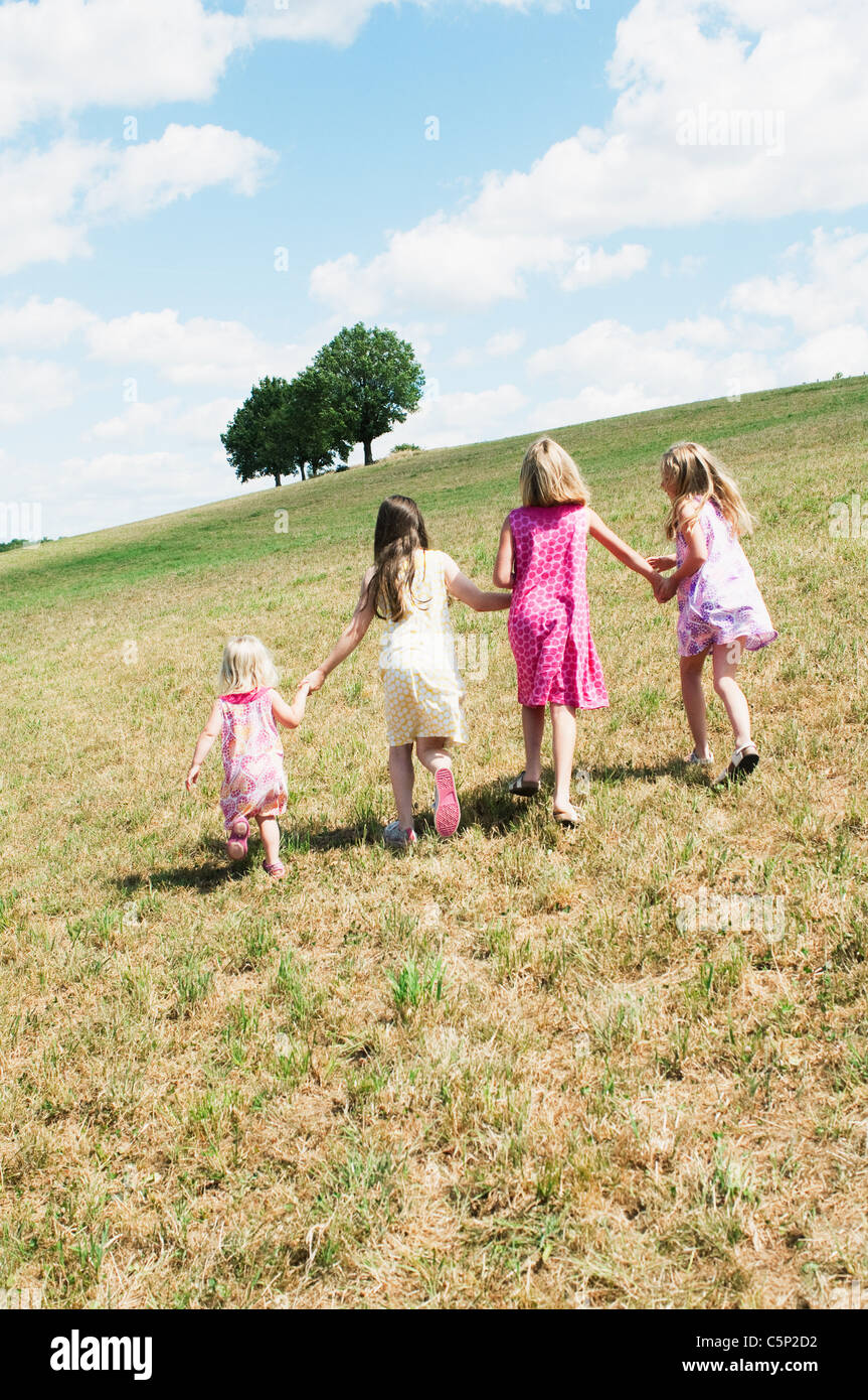 Four girls walking in field Stock Photo - Alamy