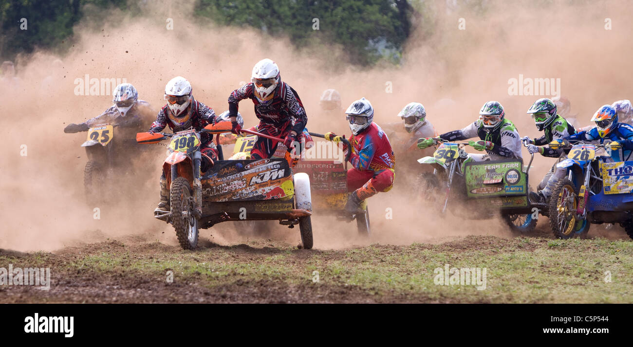 Racing through the dust at the start of a sidecar motocross race Stock Photo