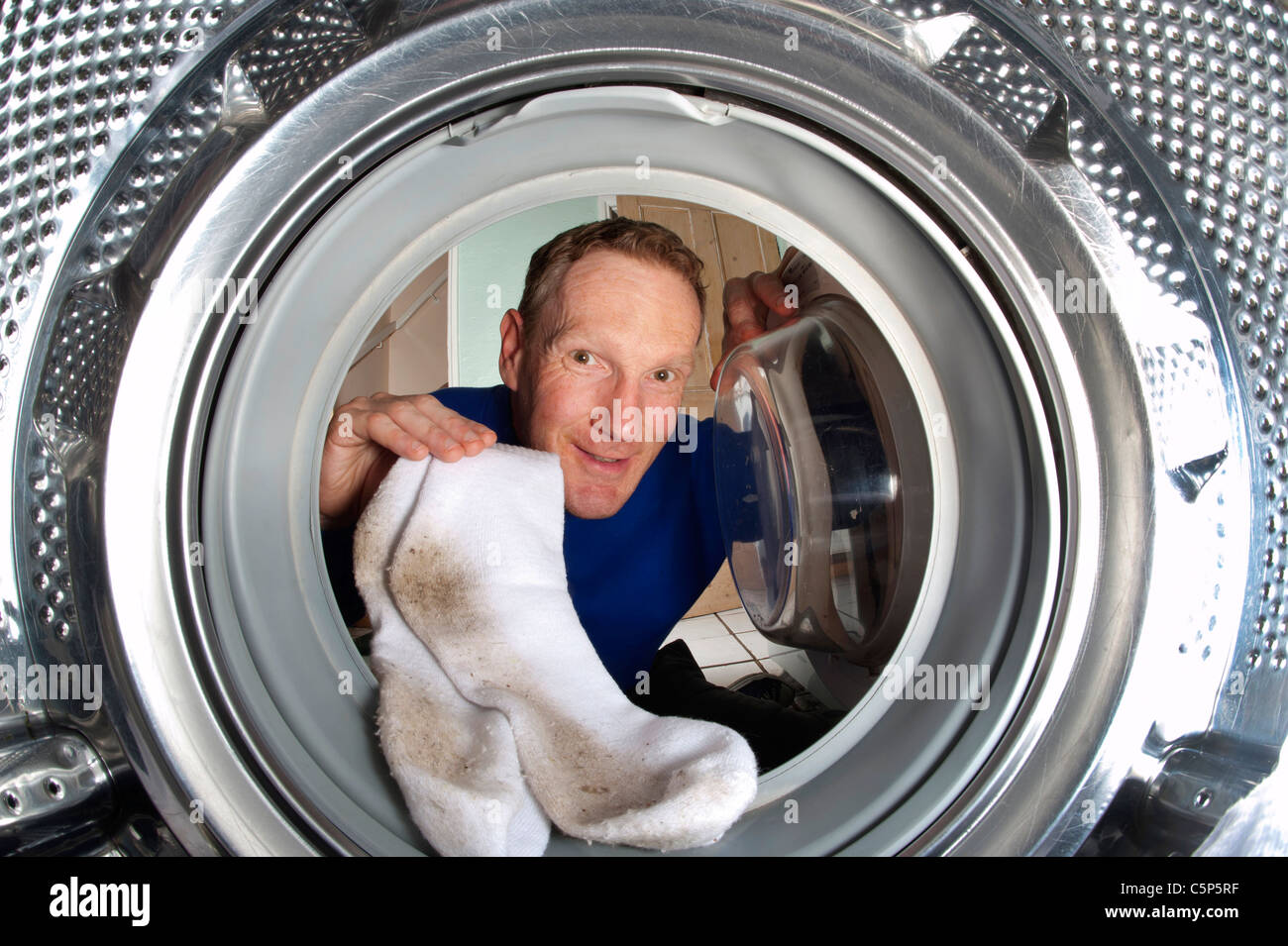 man putting dirty socks into washing machine Stock Photo