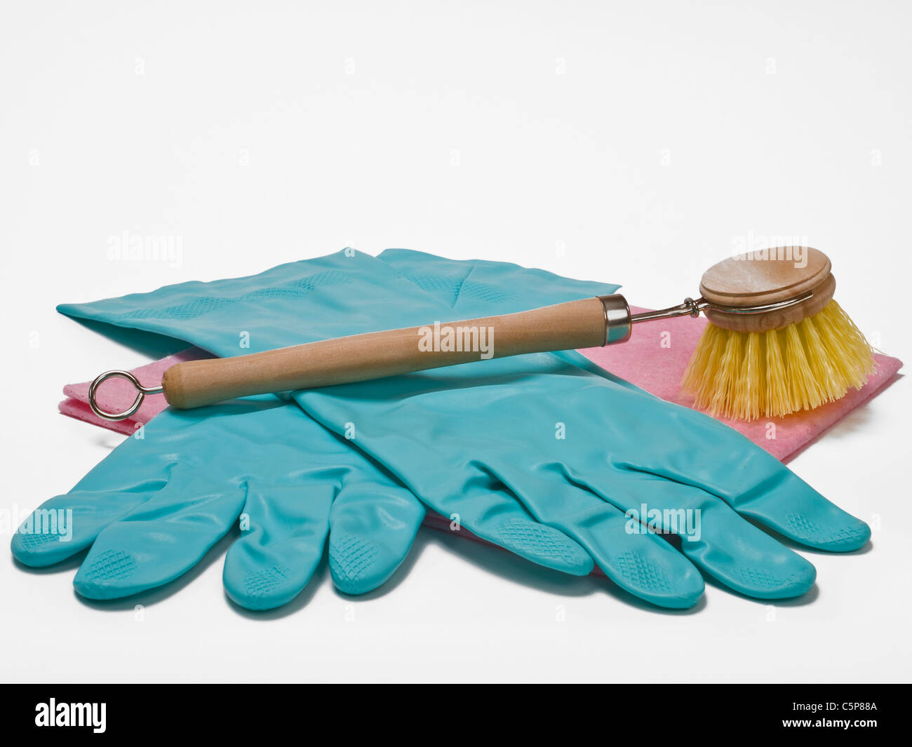 Gummihandschuhe und eine Haushaltsspülbürste liegen auf einem Lappen | rubber gloves and a washing-up brush on a cloth Stock Photo