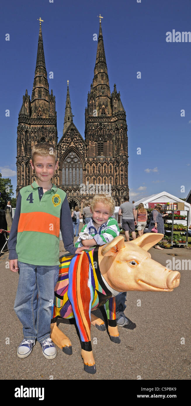 Fibreglass pig decorated for Lichfield Festival summer 2011 with two young children in front of Lichfield Cathedral Stock Photo