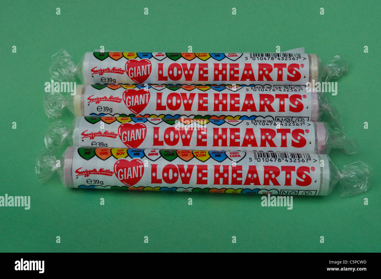 Four Love Heart Candy Sweet Packets on a green background Stock Photo