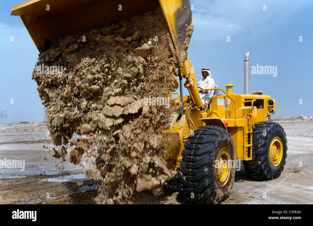 Dubai UAE Man Driving A wheeled loader Moving Sand Stock Photo