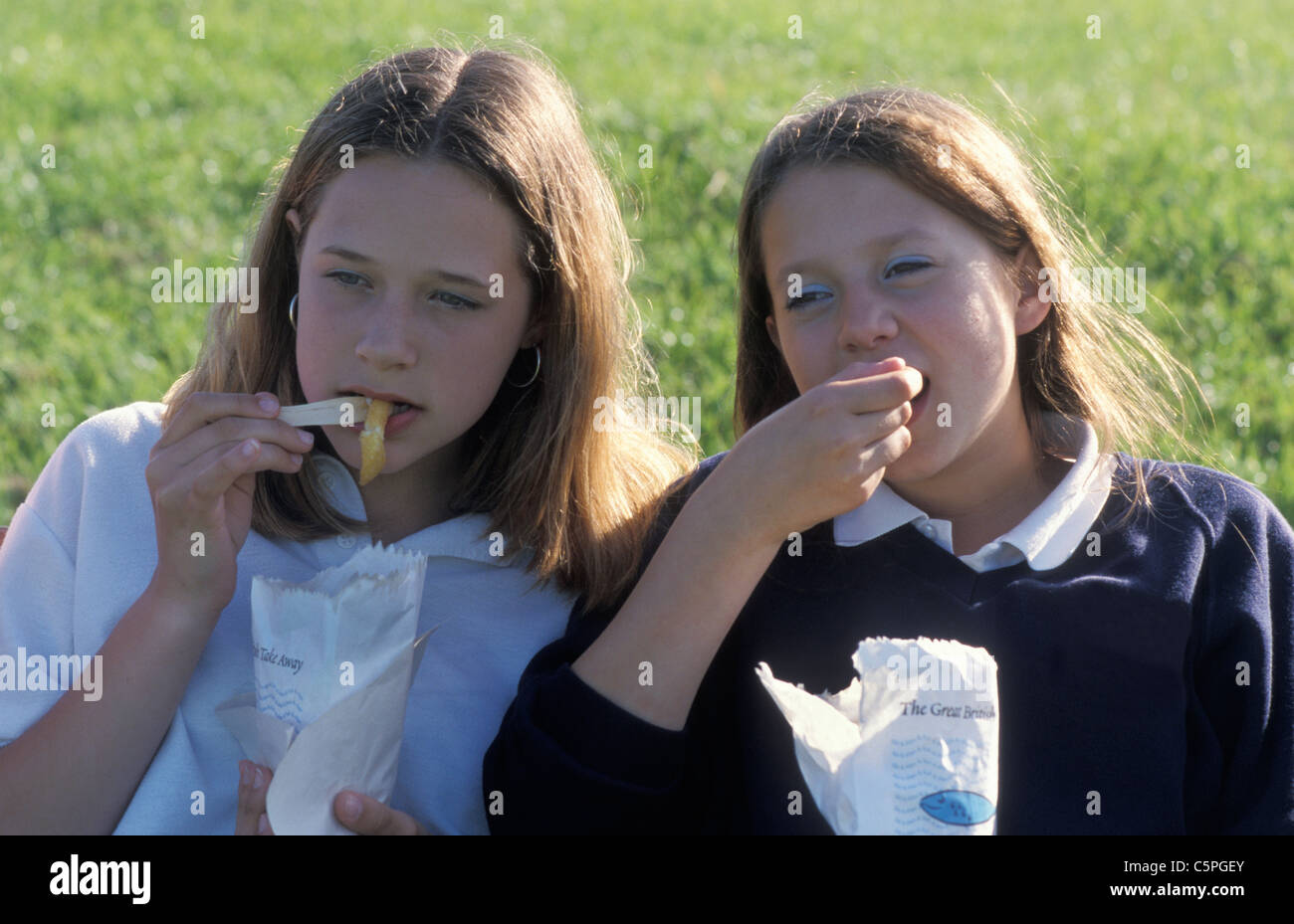 two secondary school girls eating bag of chips Stock Photo Alamy