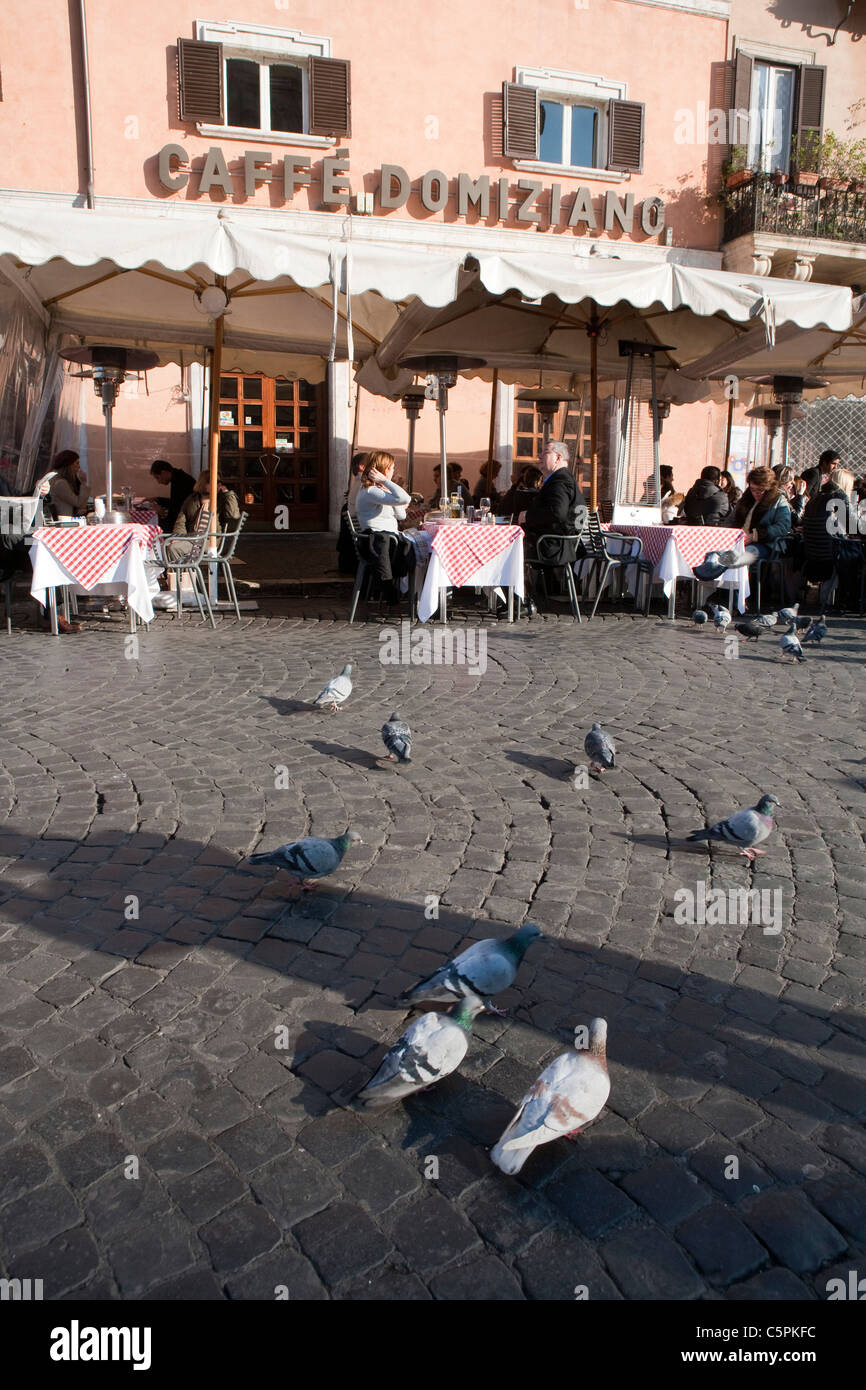 people sitting in Caffe Domiziano in Navona square Rome Italy, Pigeons on ground in first plane Stock Photo