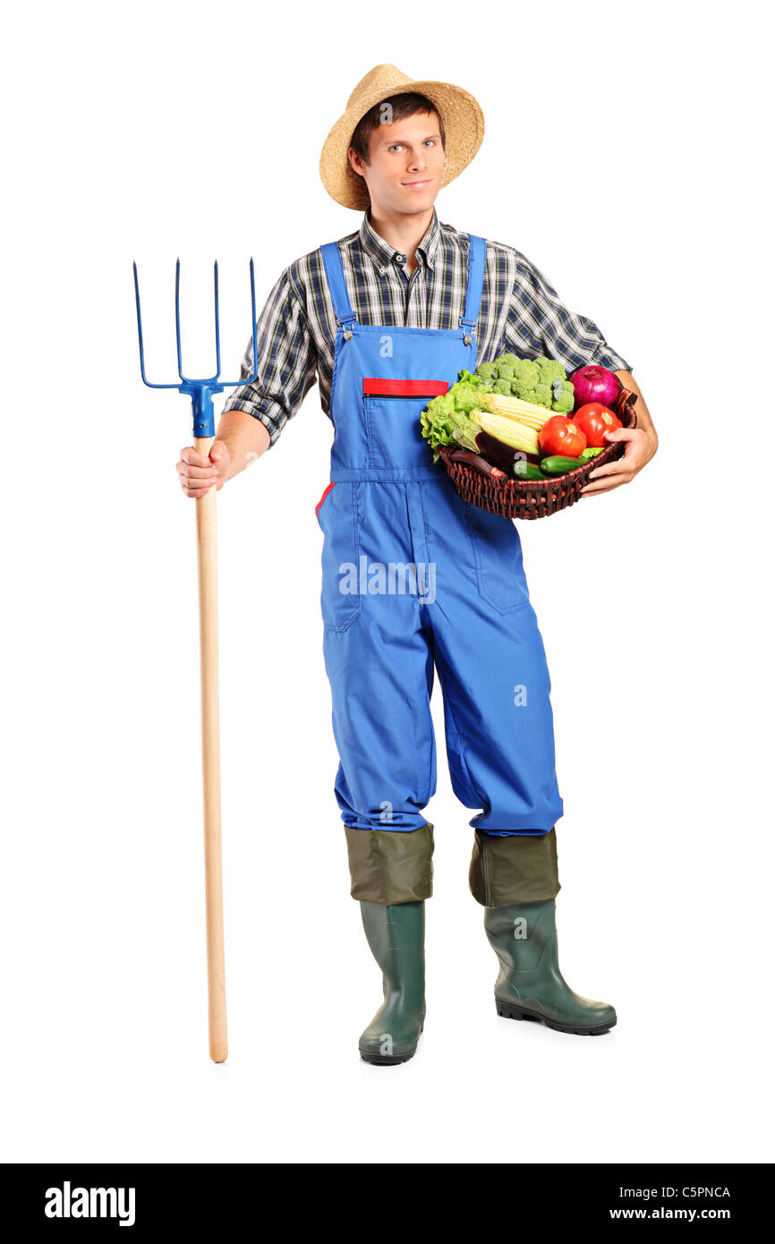 Full length portrait of a male farmer holding a pitchfork and bucket with vegetables Stock Photo