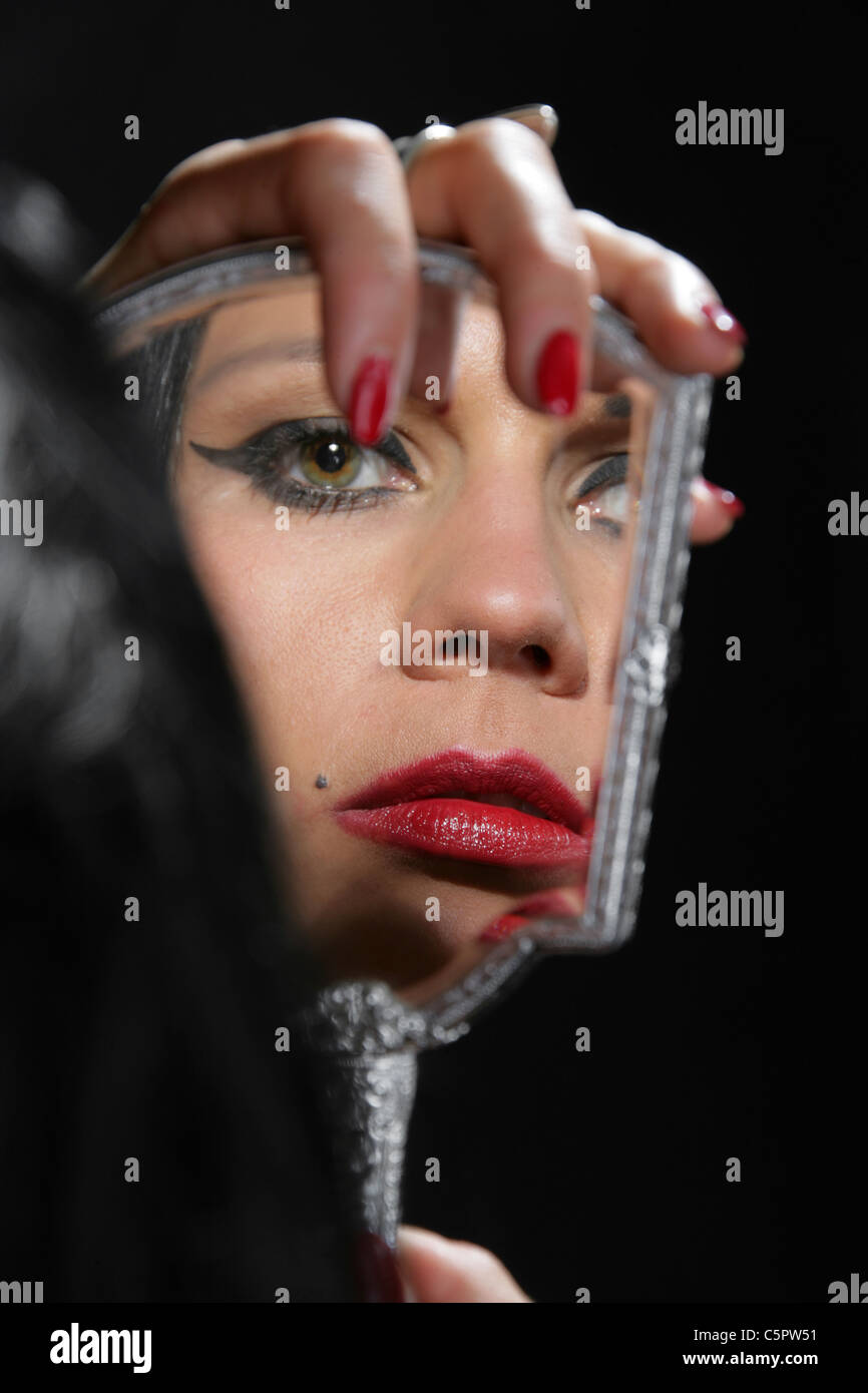 Girl Looking at Her Own Reflection in a Hand Mirror. Stock Photo