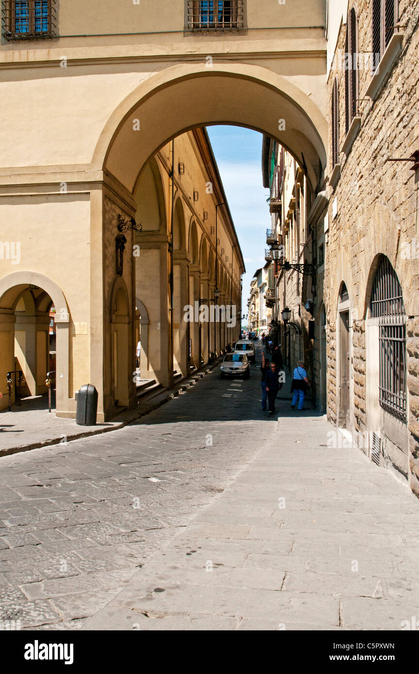 A narrow cobble stone street separating residential buildings and shops from a colonnade carrying the Vasari Corridor, Florence Stock Photo