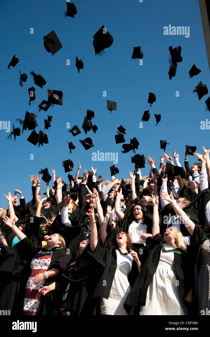 A group of Aberystwyth university students graduating on graduation day, throwing their caps in the air, UK Stock Photo