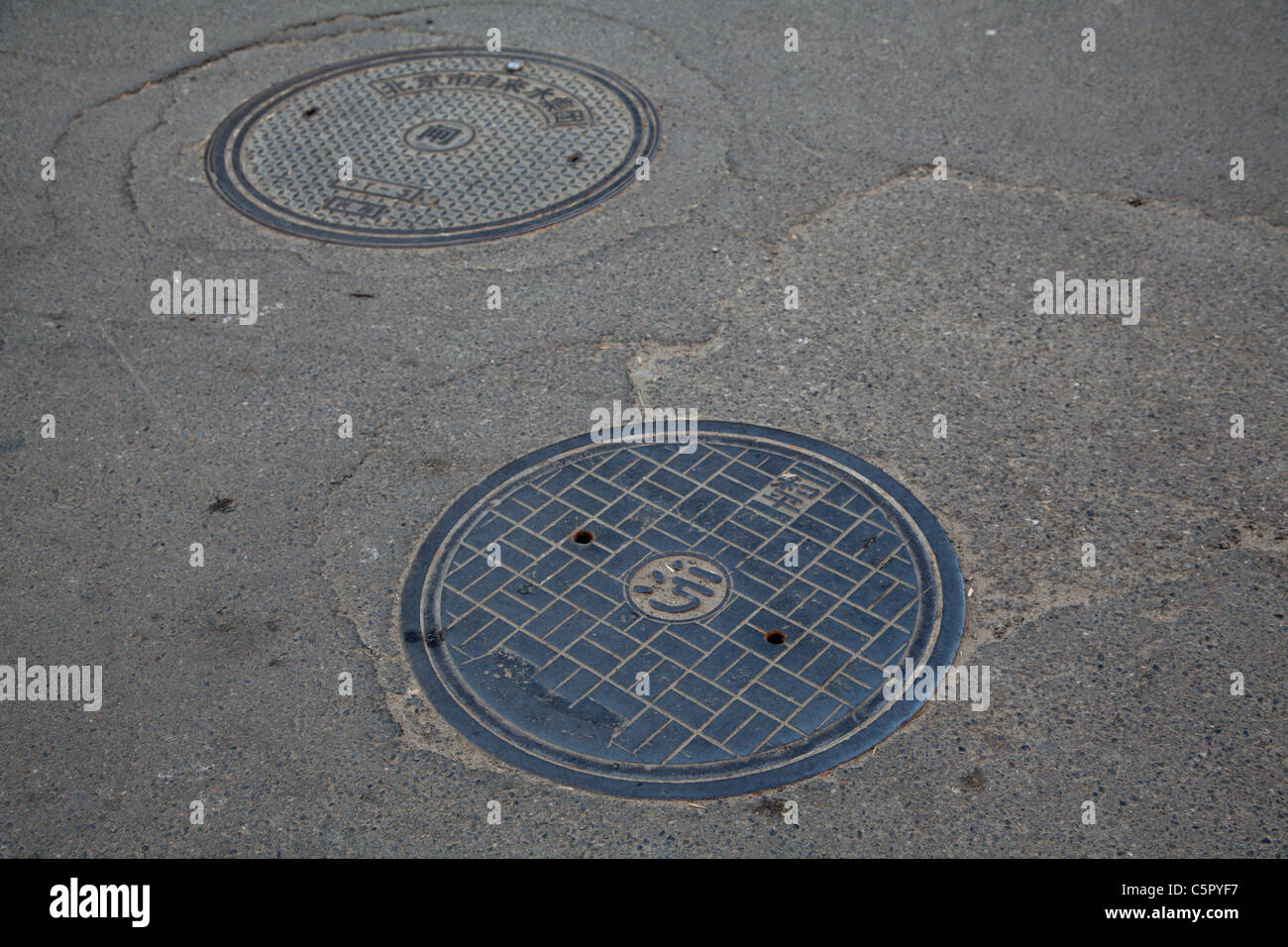 sewer drain covers in streets of Beijing, China's Hutong Village Stock Photo