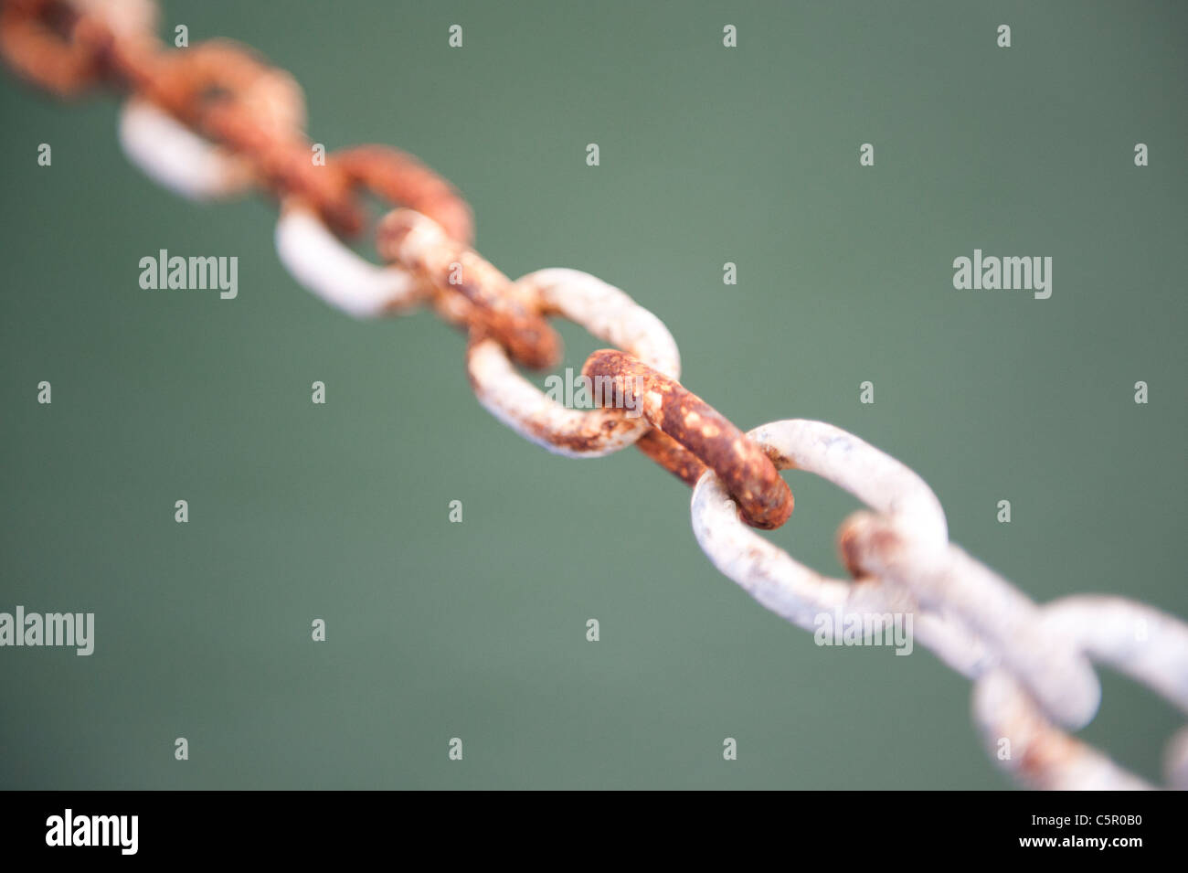 A chain painted white begins to show the effect of rust, viewed from a boat. Stock Photo
