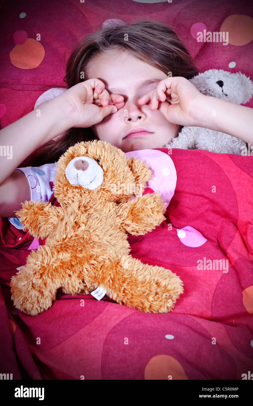 an eightyearold girl in bed with blanket and pillows and stuffed