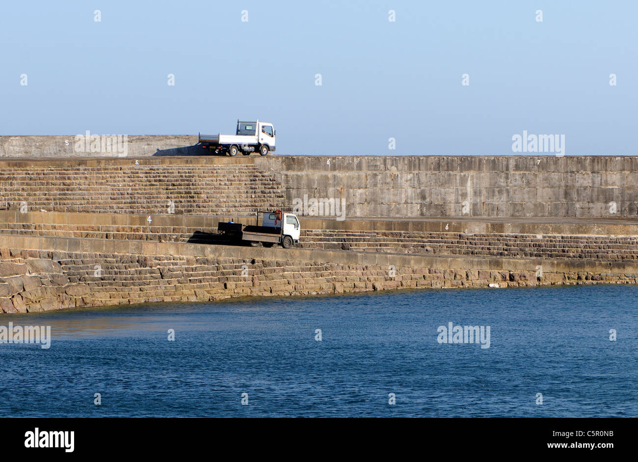 Two trucks on the massive victorian Braye Harbour breakwater.  Alderney, Channel Islands, UK. 29Jun11 Stock Photo