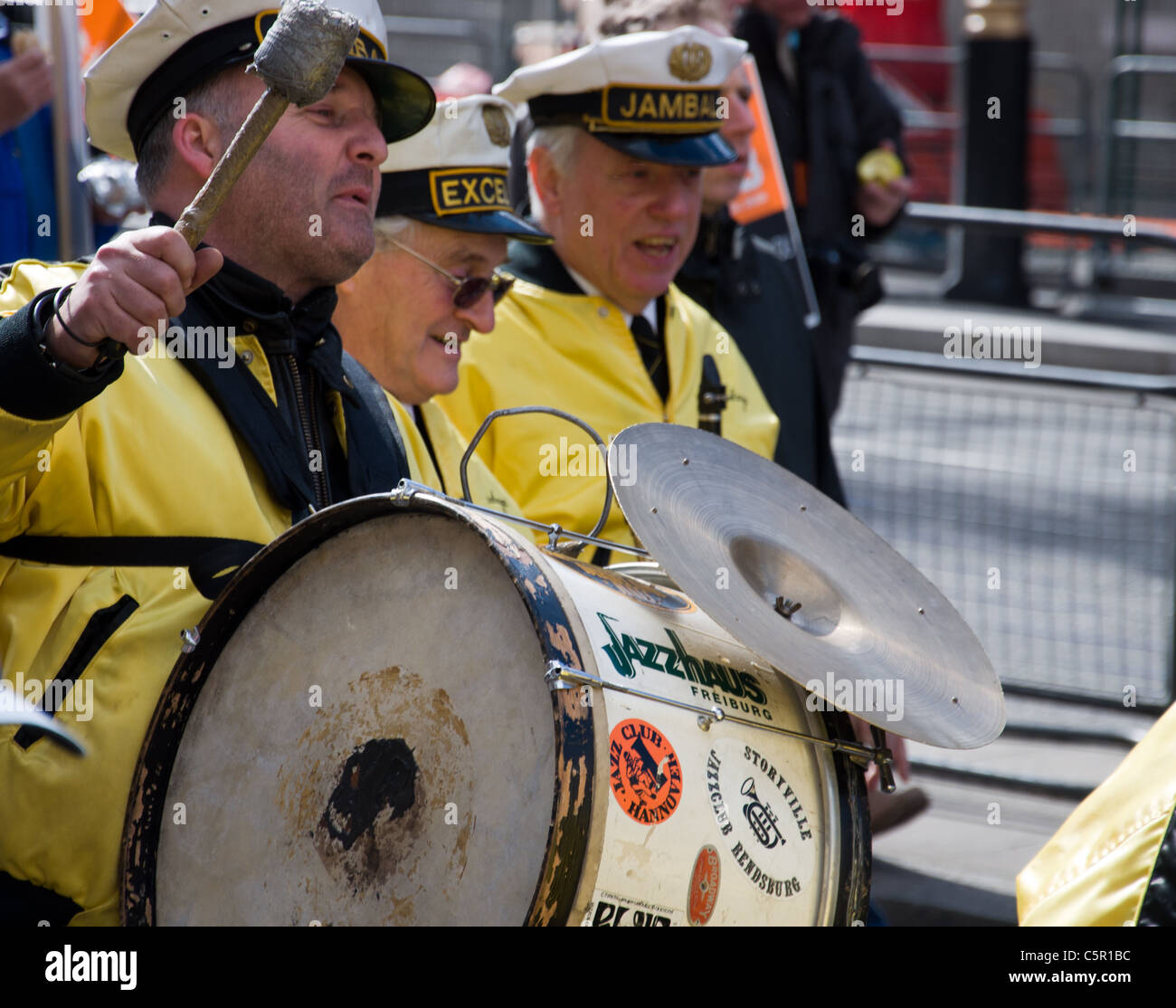Brass band members in bright yellow jackets with drums at G20 March in