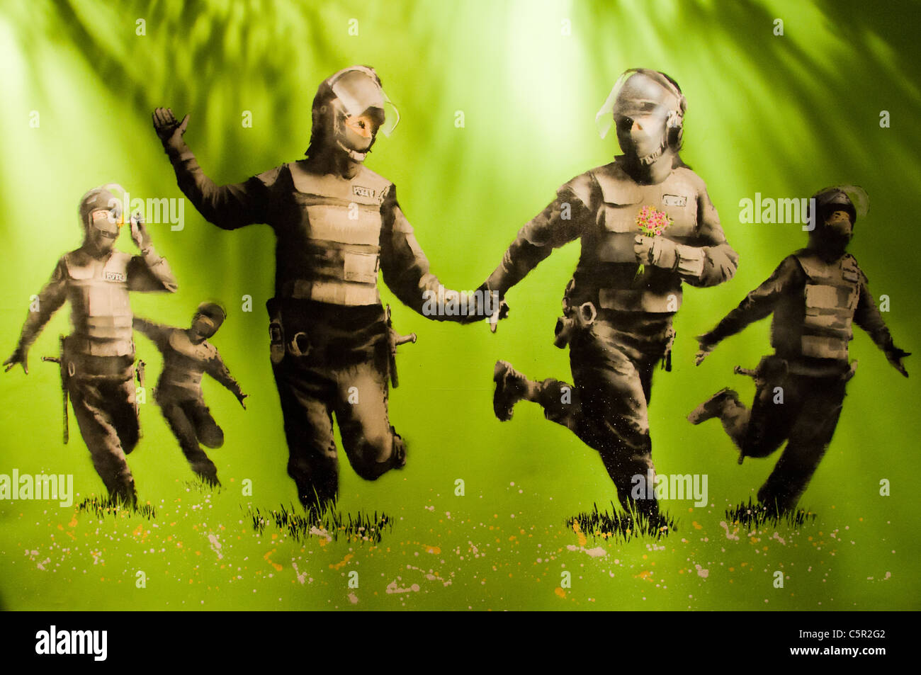 Banksy picture of 5 riot police skipping through daisies holding hands Stock Photo