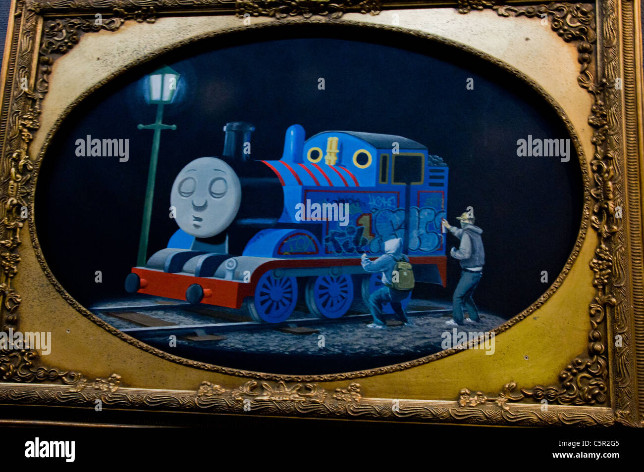 Banksy picture of Thomas the Tank Engine sleeping whilst 2 youths spray grafitti on him Stock Photo