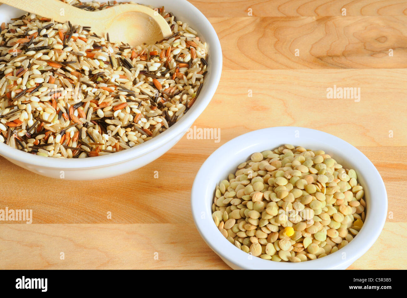Bowls of uncooked wild rice and lentils on a cutting board Stock Photo