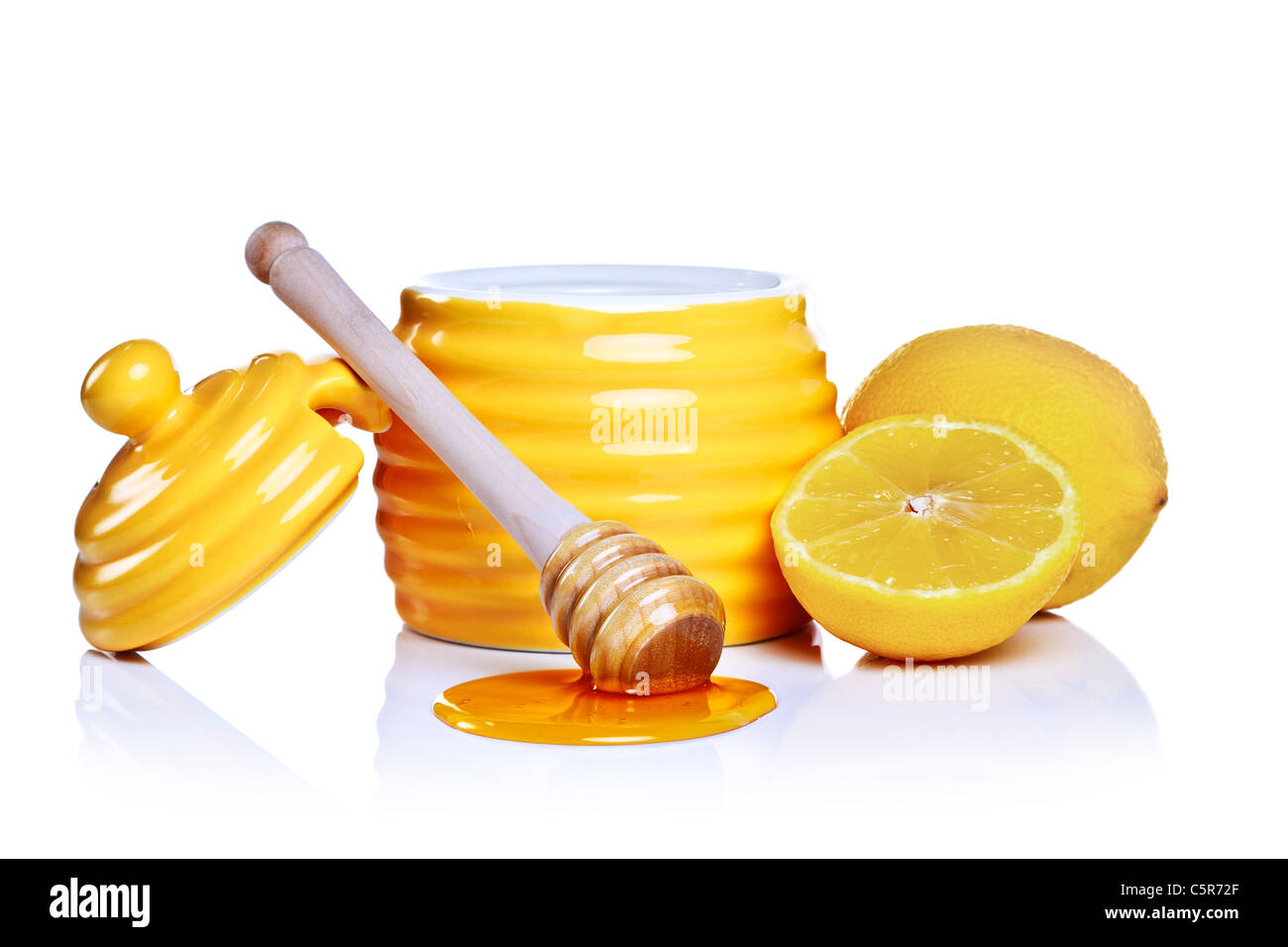 Photo of a beehive shaped honey pot with dipper and lemon isolated on a white background. Stock Photo
