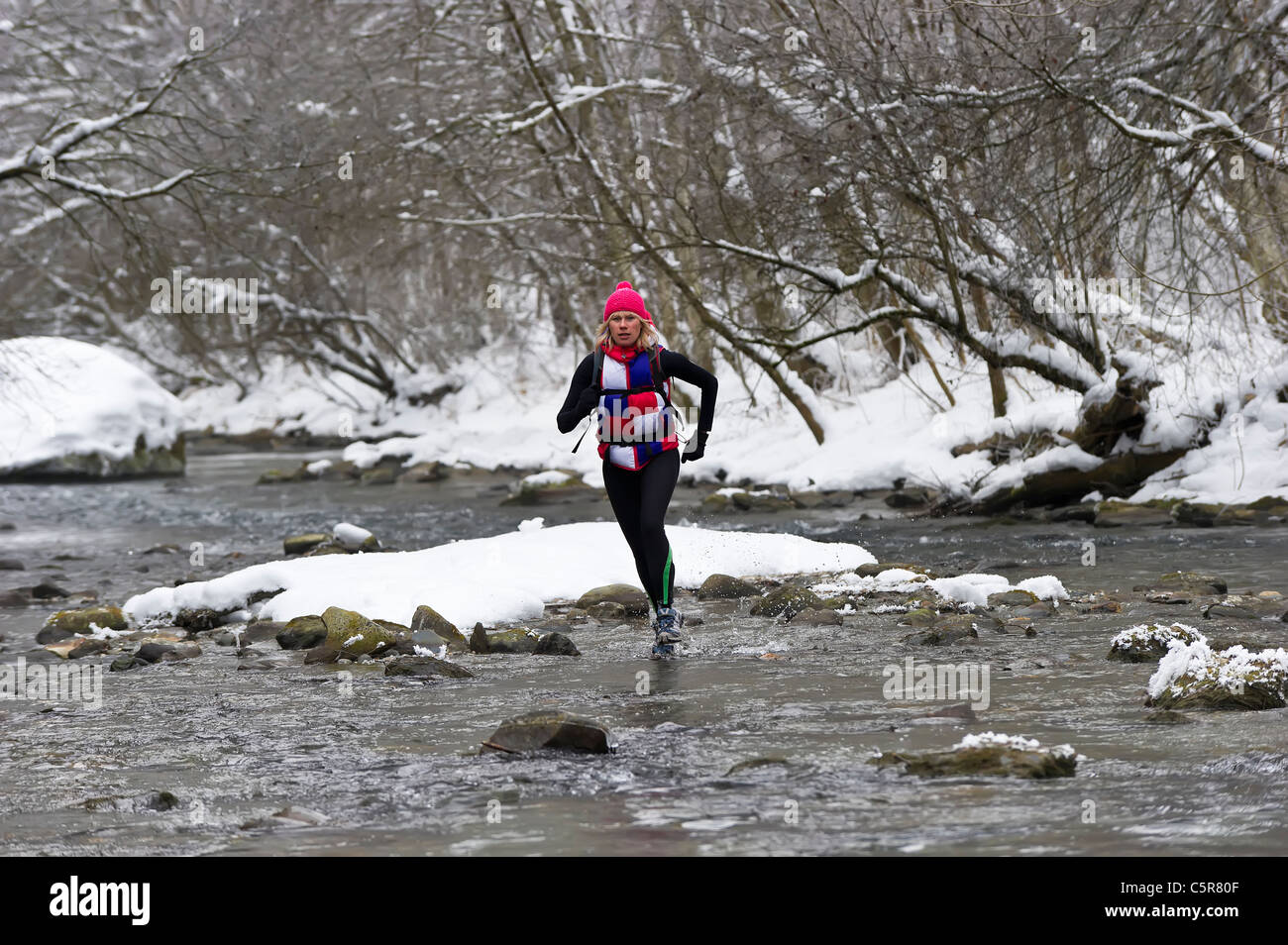 A jogger crossing a snowy river. Stock Photo