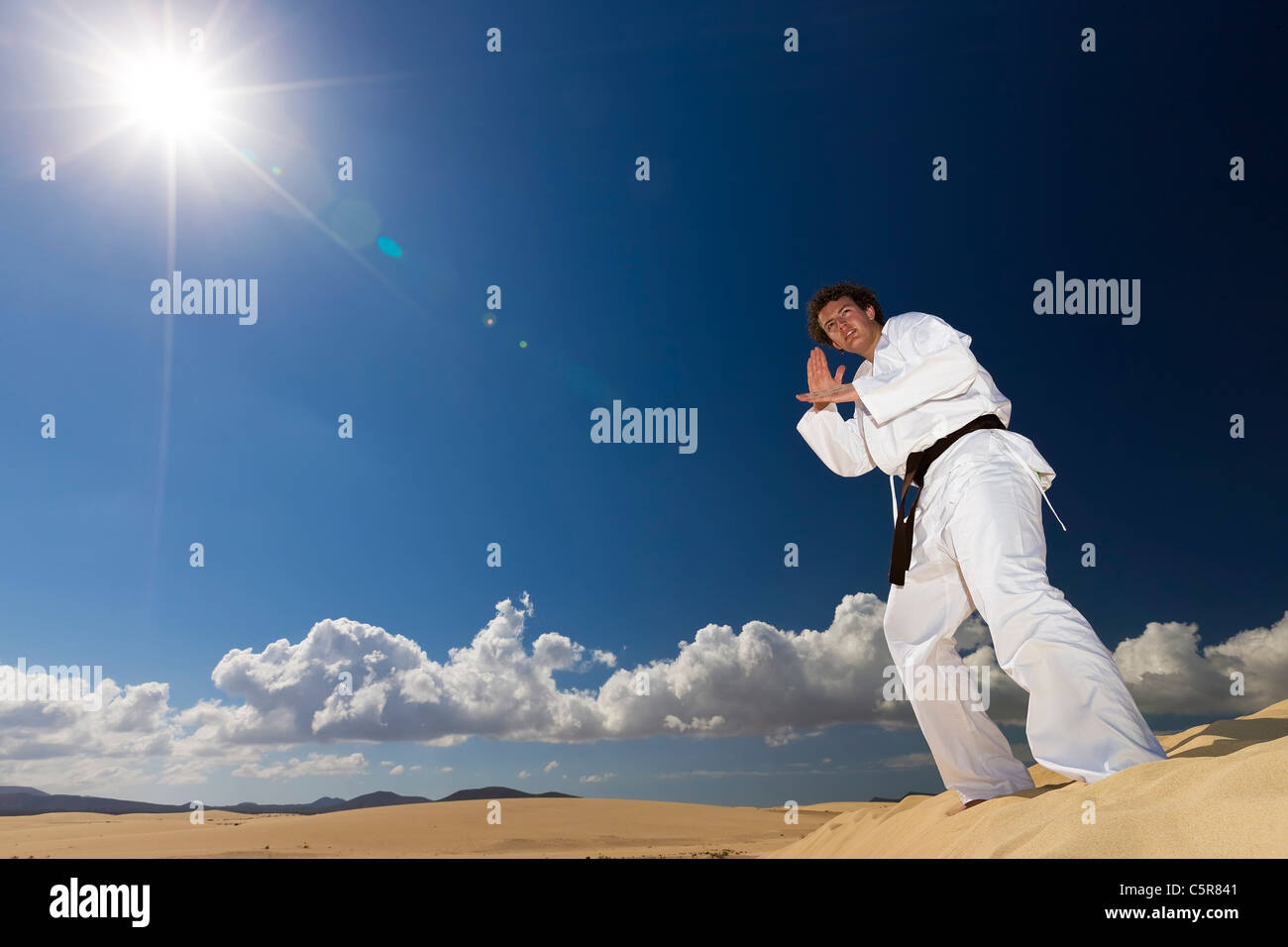 Black belt martial artist training on desert dunes. Stock Photo