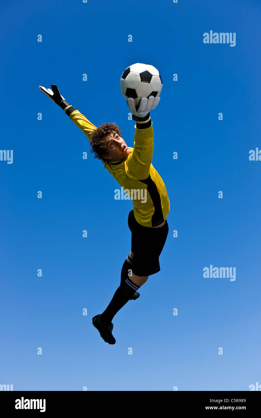 A Goalkeeper succeeds in getting a hand to the ball. Stock Photo