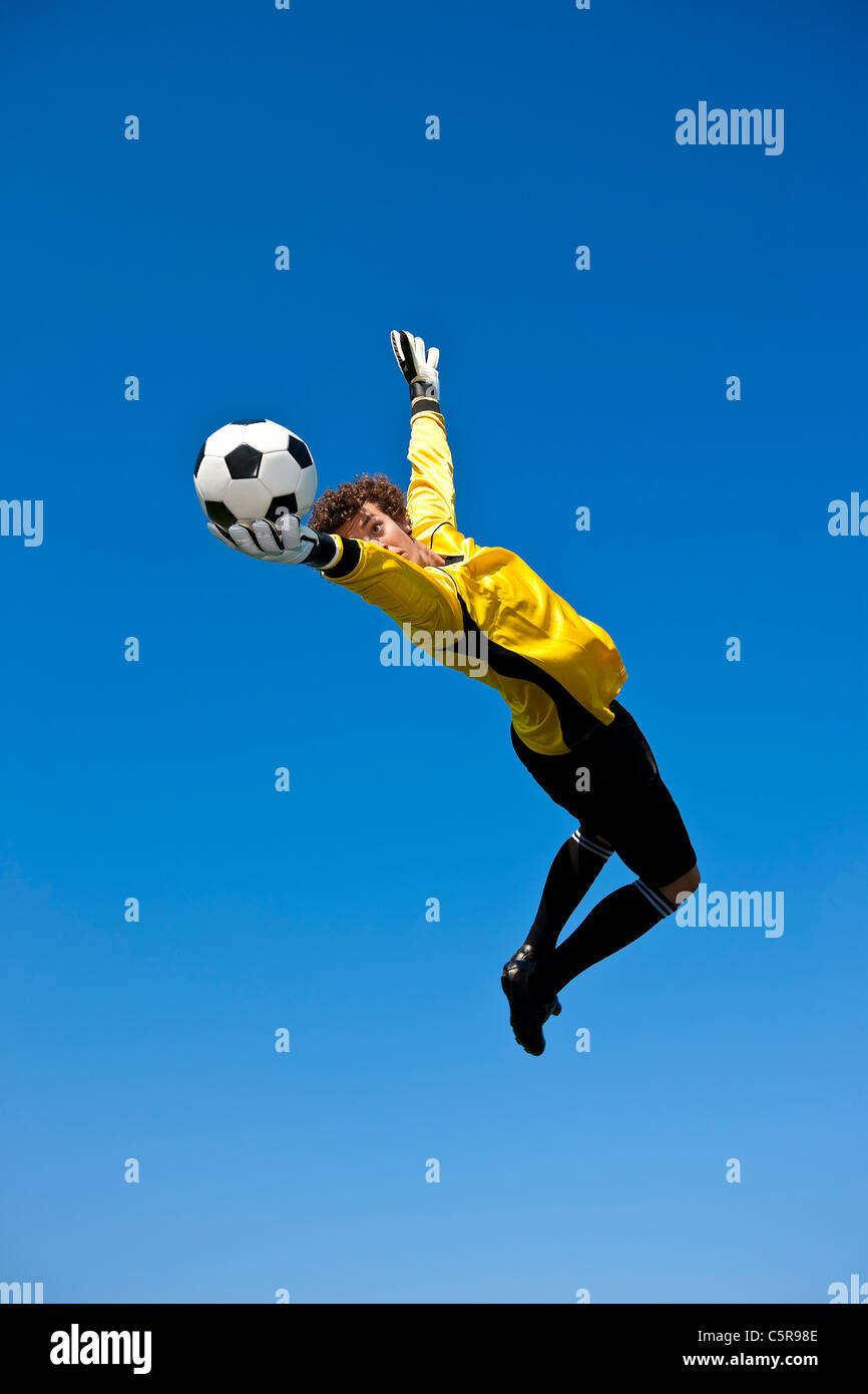 A goalkeeper keeps one eye on the ball and makes the save. Stock Photo