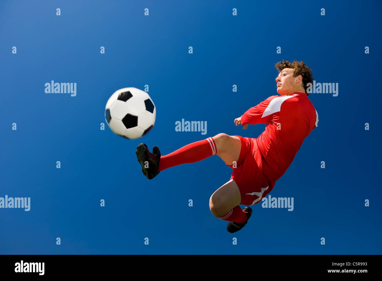 A soccer player volleys a ball in mid air. Stock Photo