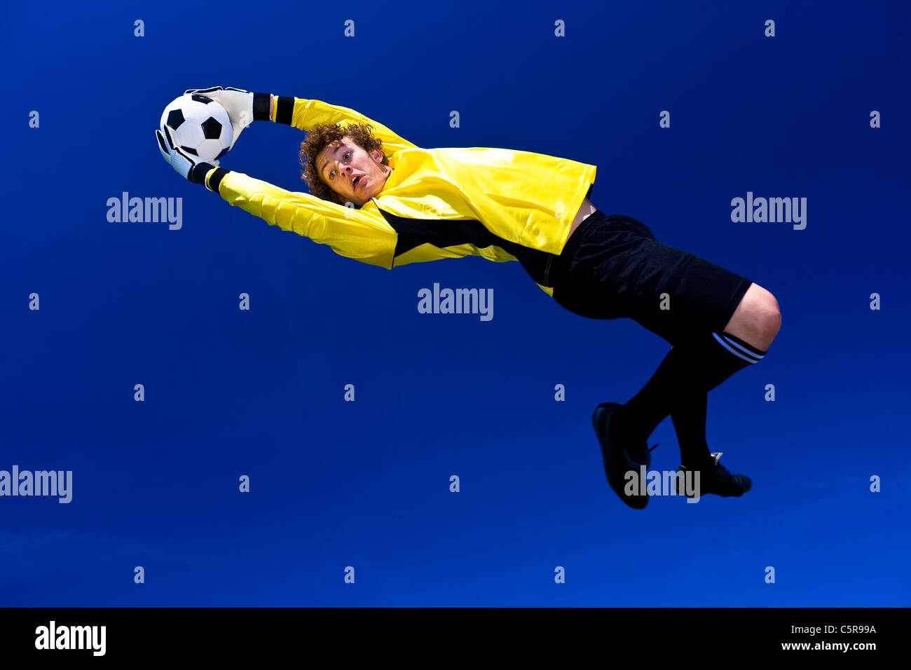 A goalkeeper stretches to make the save. Stock Photo