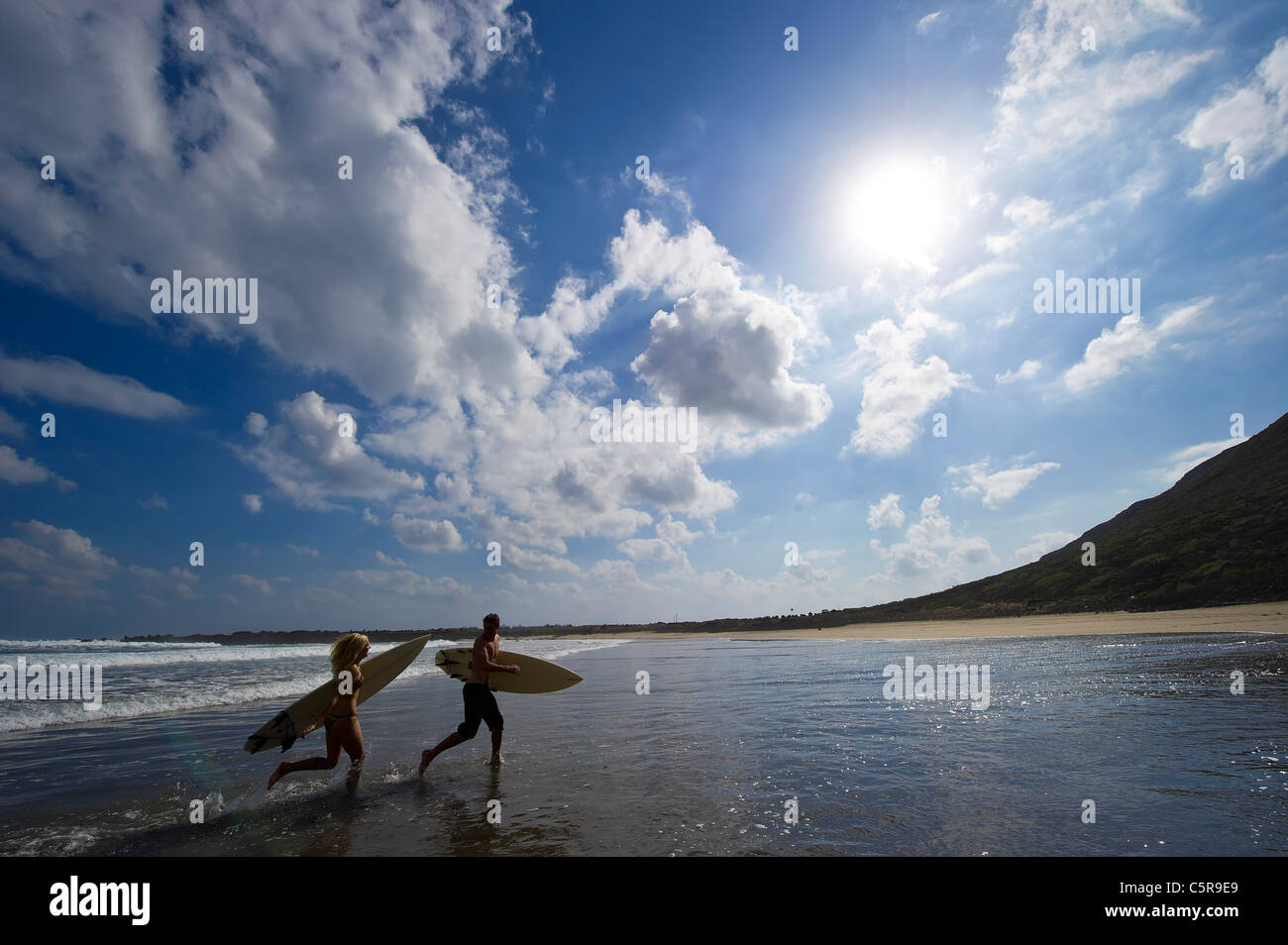 Two surfers running along the beach having fun Stock Photo Alamy