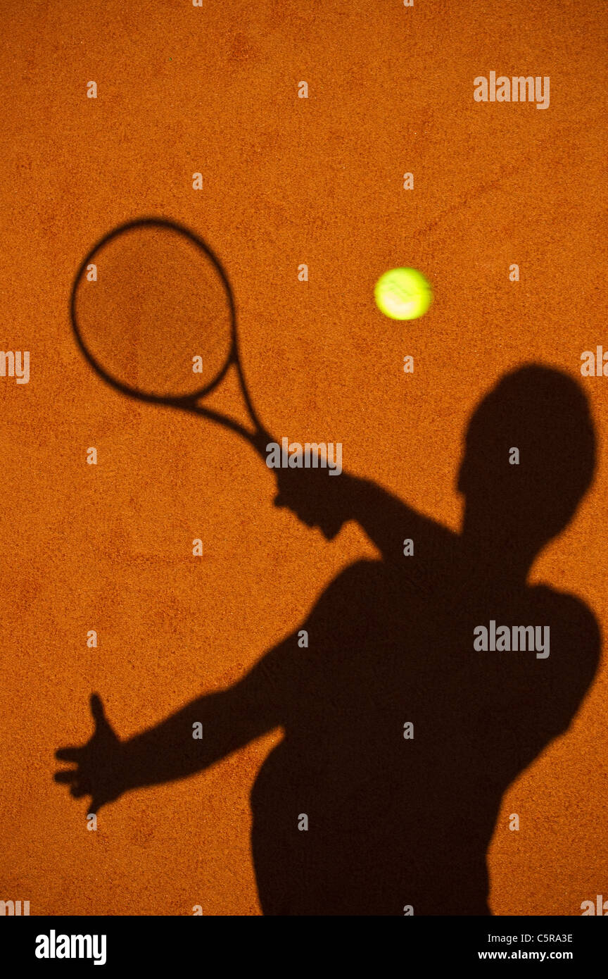 A tennis player silhouette playing the shot. Stock Photo