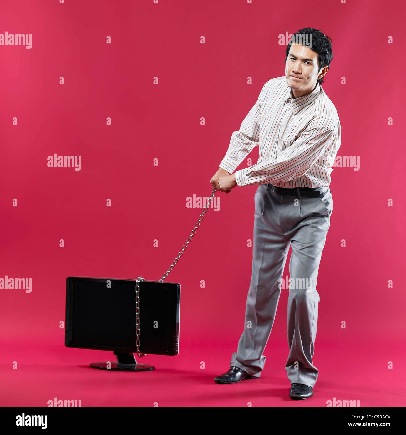 A man pulling a monitor with chain Stock Photo
