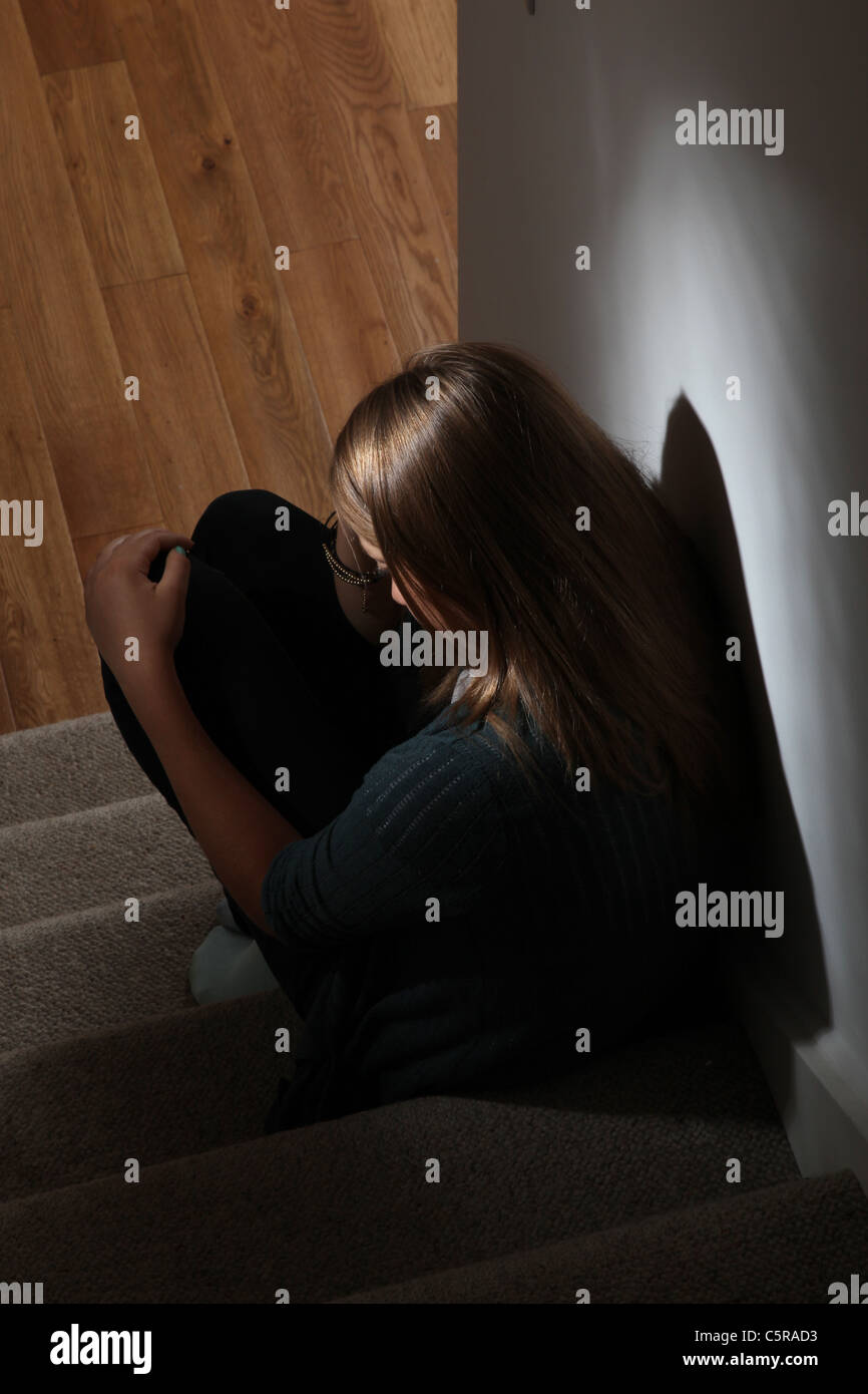 Young girl sitting on dark stairs back view Stock Photo