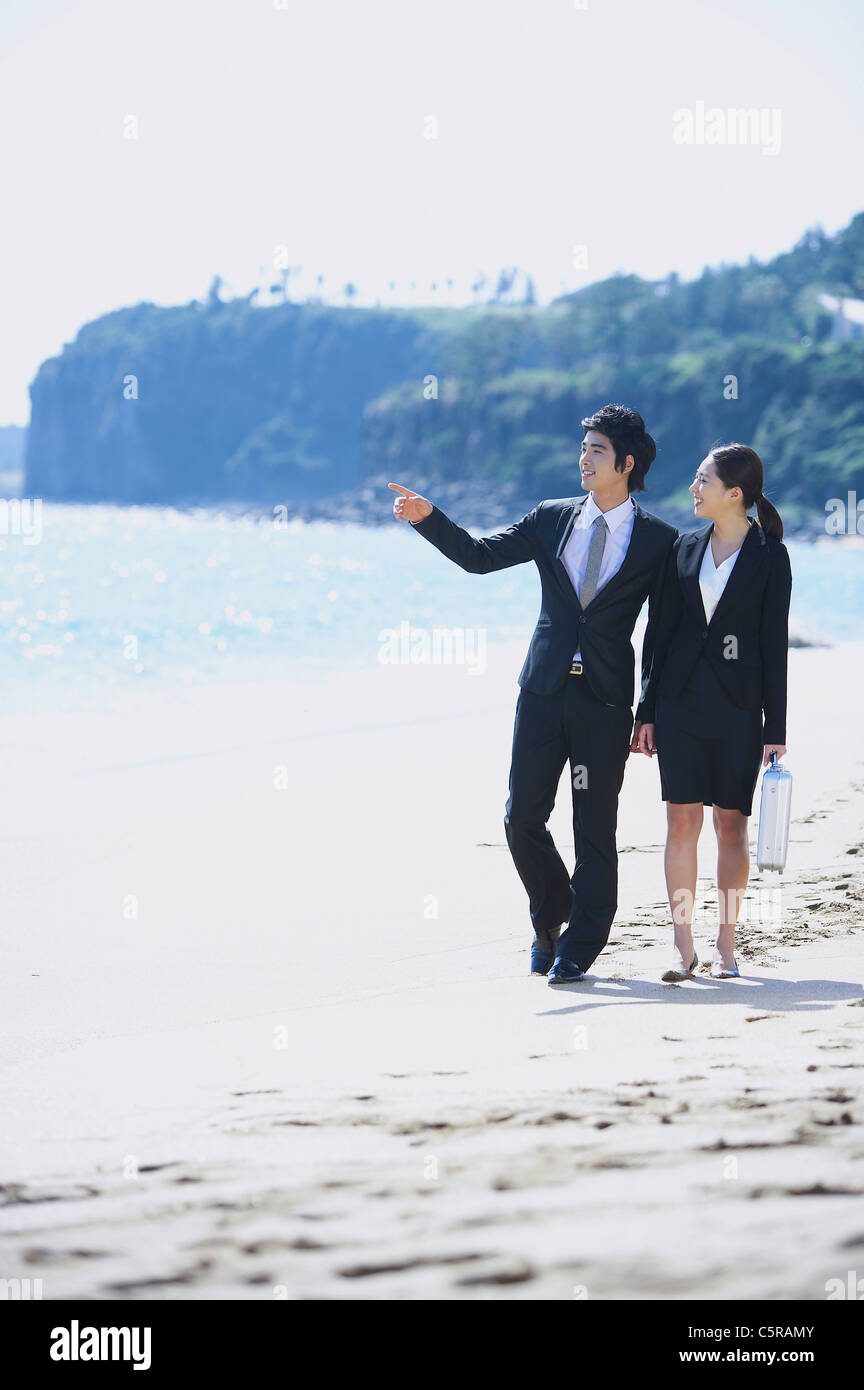 A man and a woman walking on a beach Stock Photo - Alamy