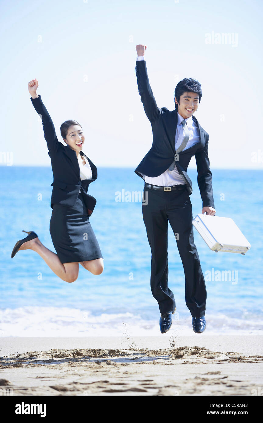 Two people jumping together at the beach Stock Photo