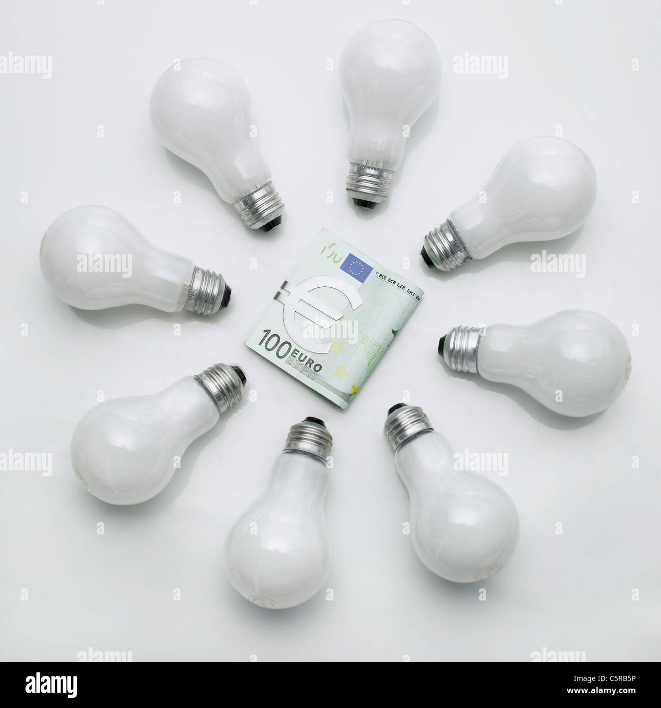 Paper money surrounded by light bulbs Stock Photo