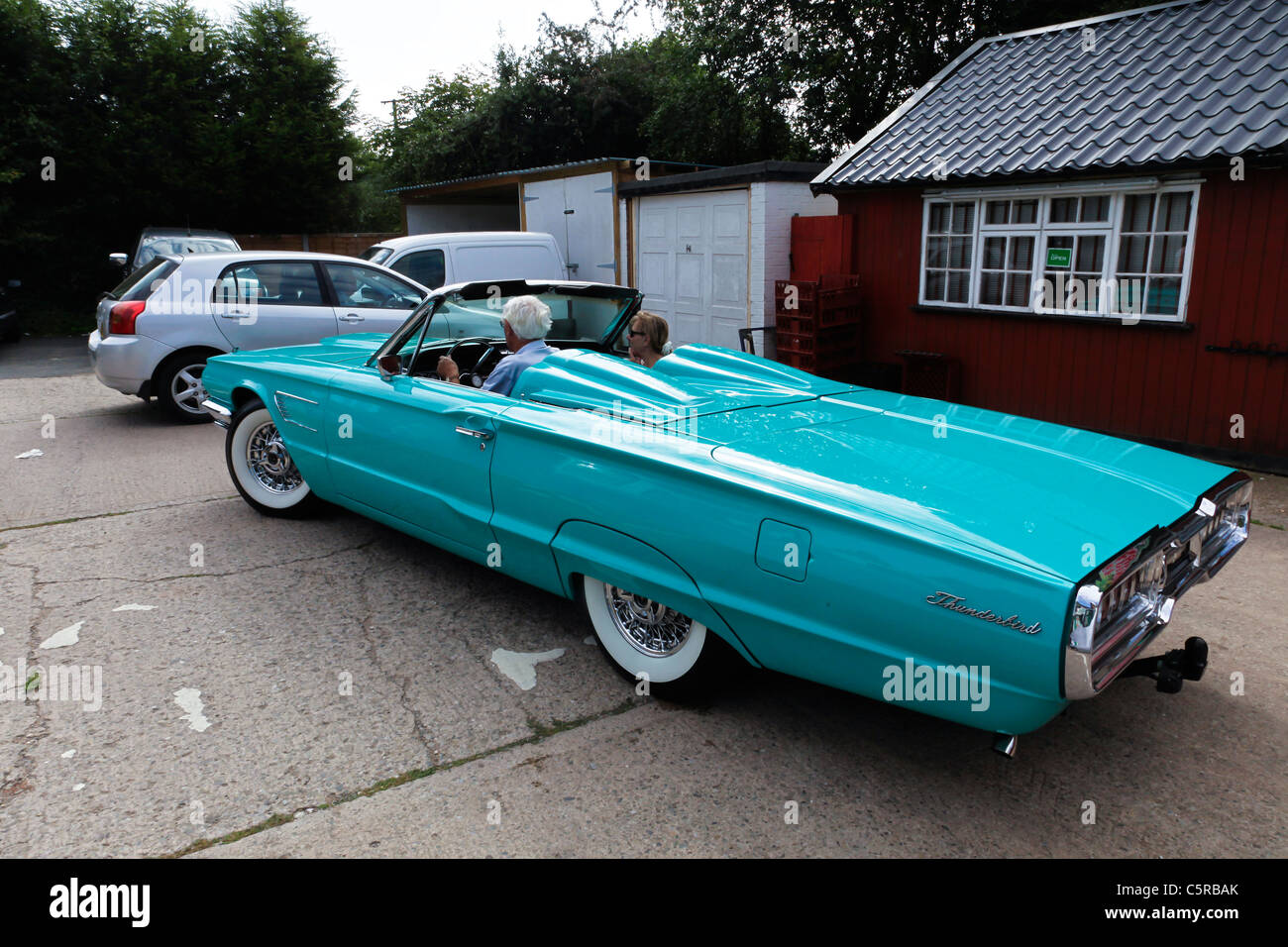 A 1965 pale blue Ford Thunderbird convertible with a mature couple driving  in it Stock Photo - Alamy, image size:1300x956