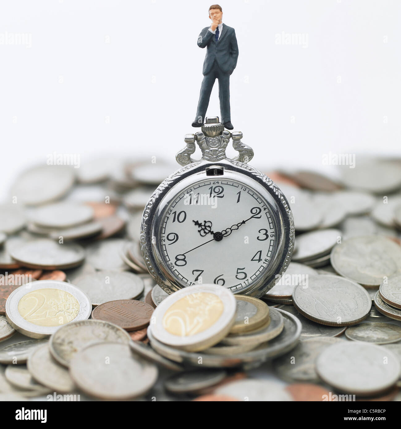 A figurine on a pocket watch and coins Stock Photo