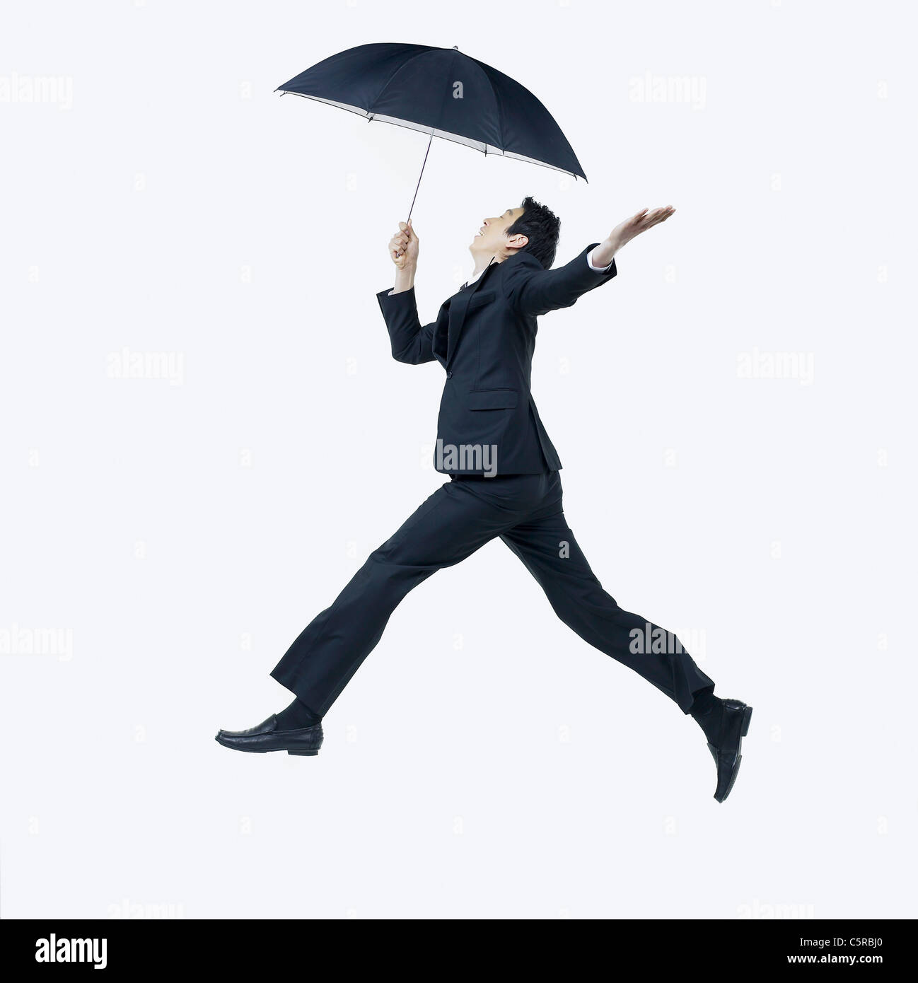 A man holding an umbrella and jumping Stock Photo