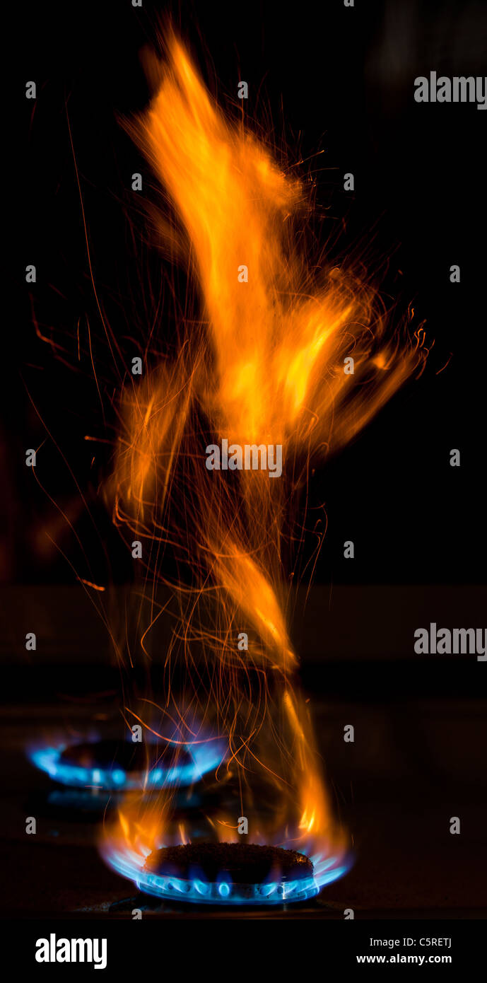 sparks and flames above gas stove burning with blue flames Stock Photo
