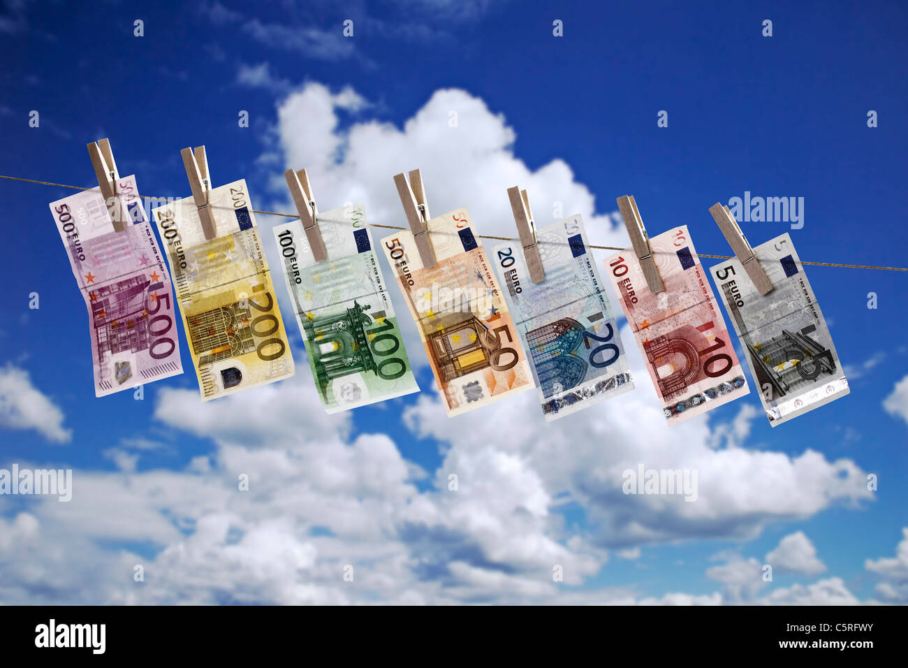 Different Euro bank notes hanging on clothesline against cloudy sky Stock Photo
