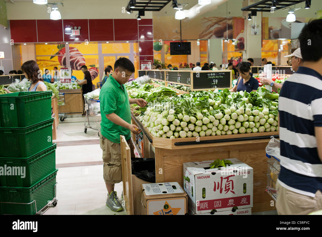 An Employee Stocks Bok Choy At The New Sky Foods Supermarket In